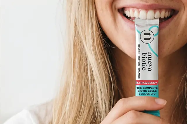 Woman holding a Nueva Biotic strawberry stick pack