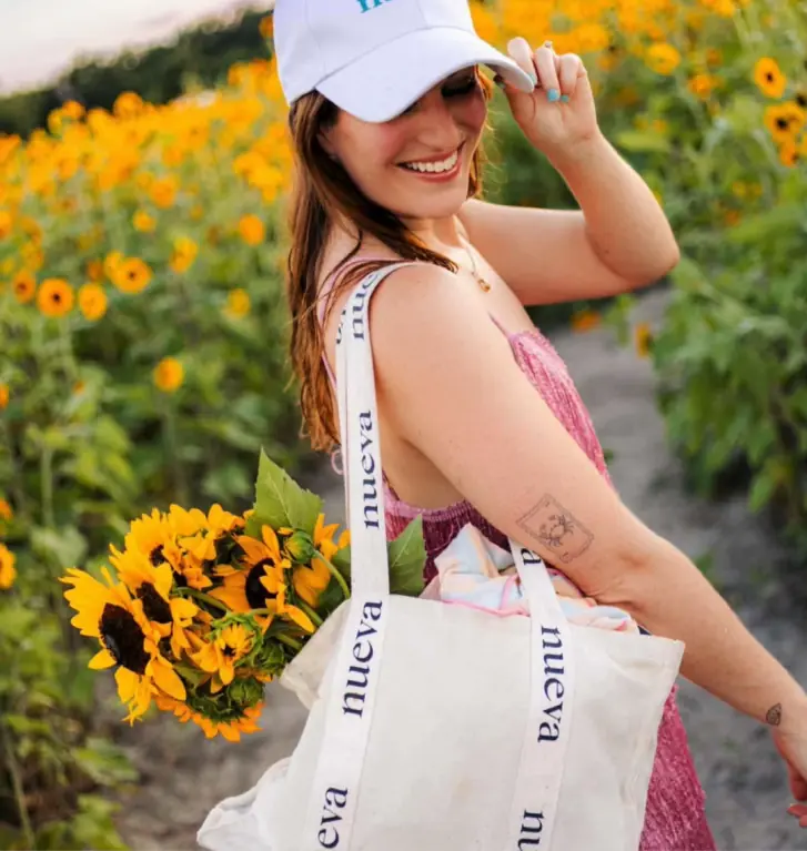 Smiling woman carrying sunflowers in a Nueva tote bag